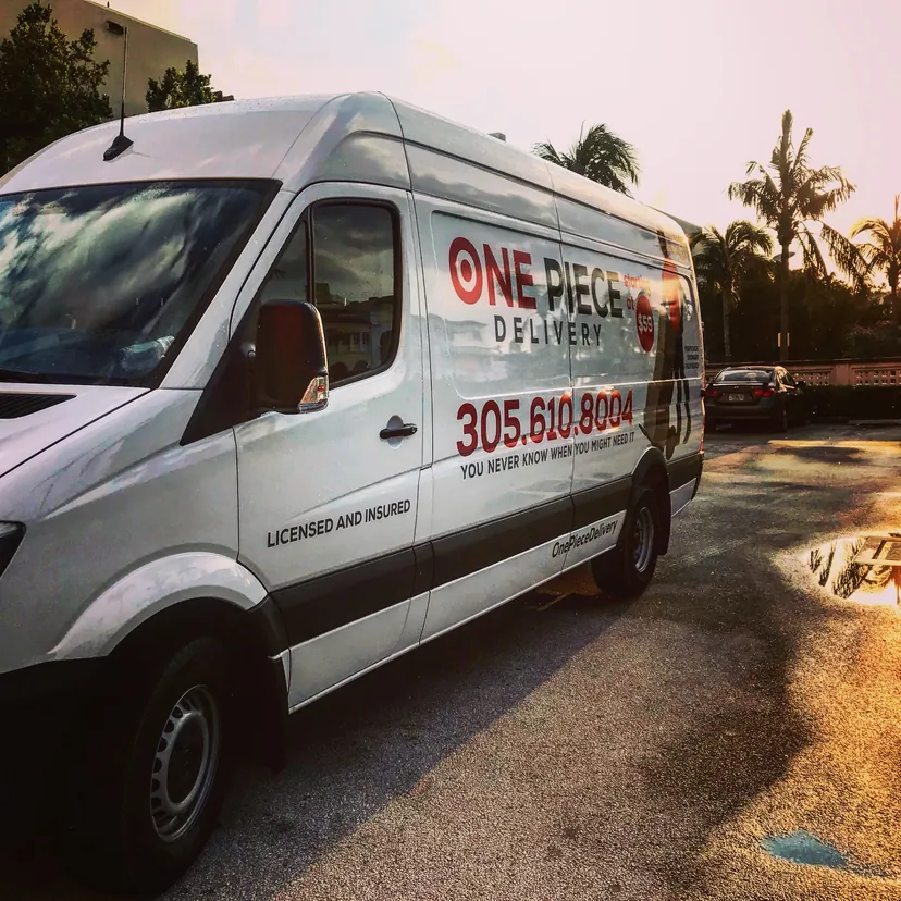 Una de las primeras vans de techo alto de One Piece Delivery estacionada bajo palmeras al atardecer.